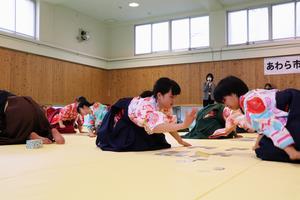 袴姿で札を払う参加者の写真