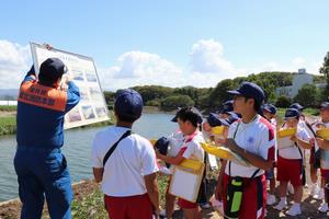 竹田川で話を聞く児童の写真