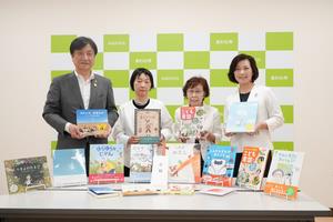 絵本を持って記念撮影する様子